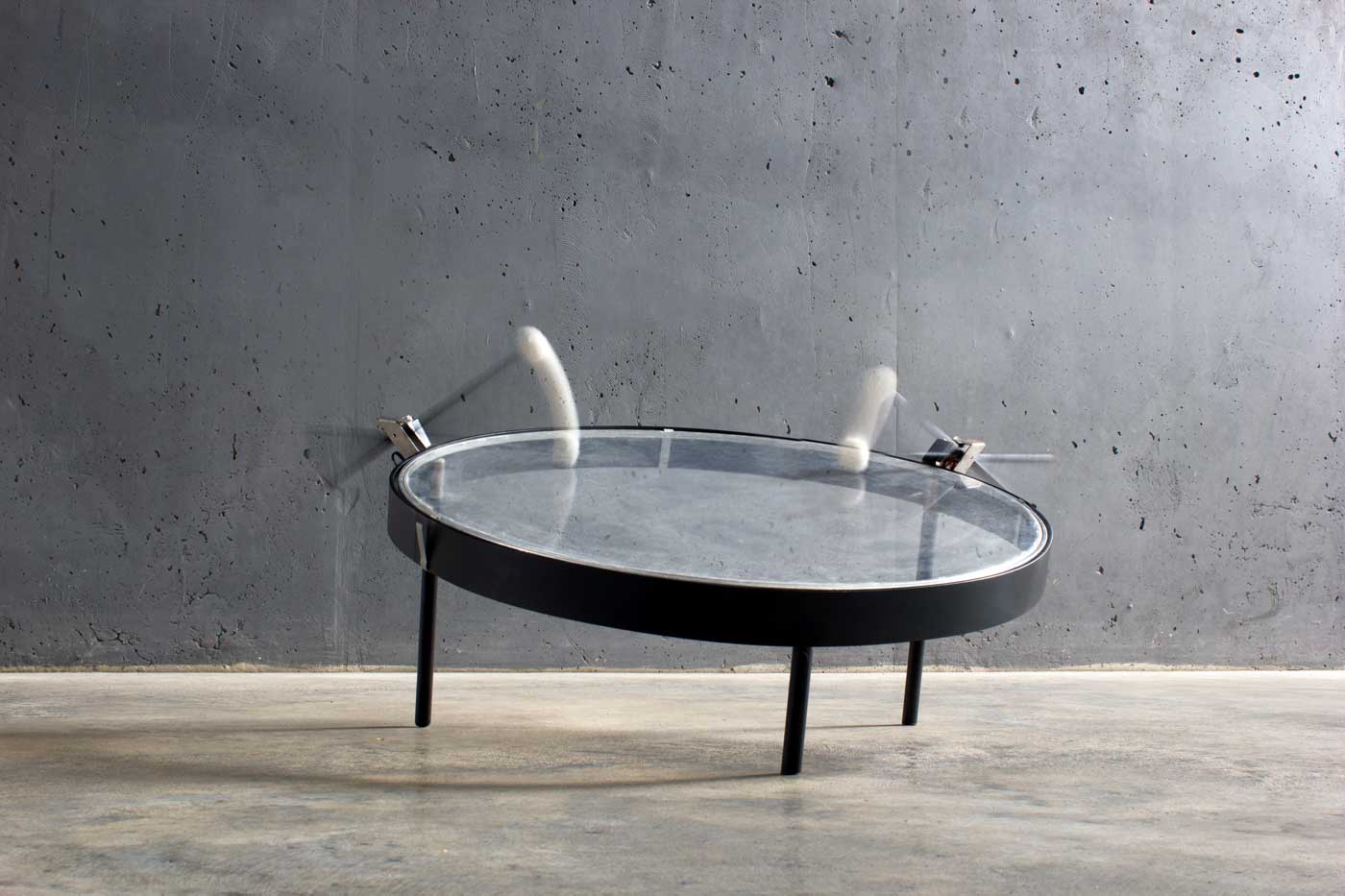 An exhibition photo, a large transparent drum frame being struck by mallets.