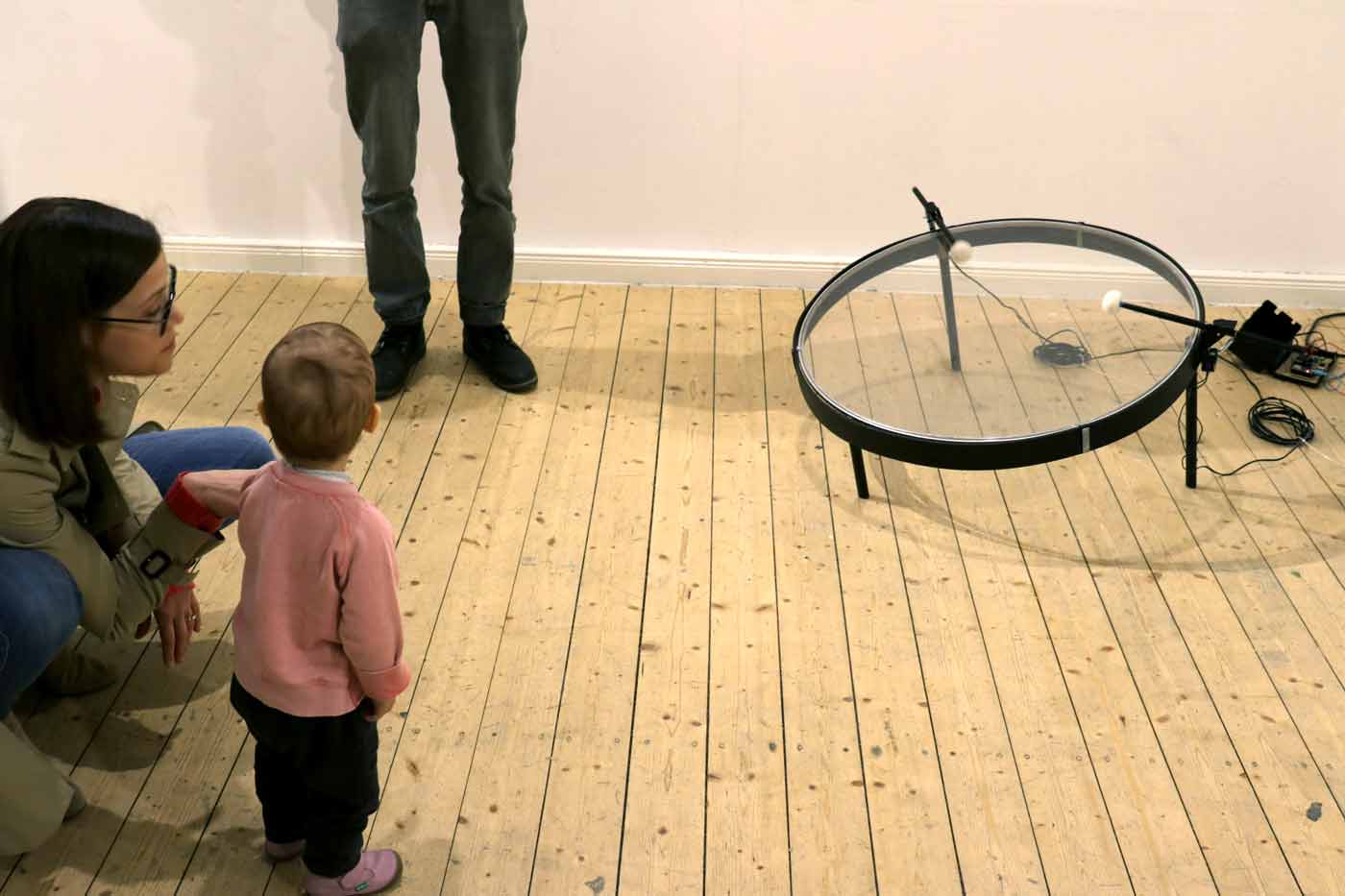 Gallery goers, a woman and toddler, are examining the artwork.