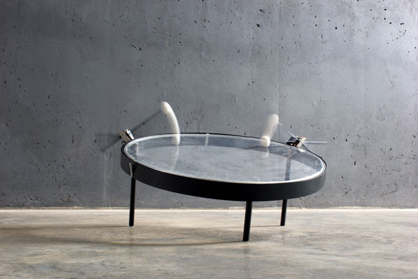An exhibition photo, a large transparent drum frame being struck by mallets.
