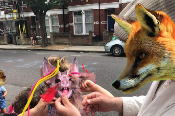 A child wearing a bat mask and an adult wearing a fox mask on the street.